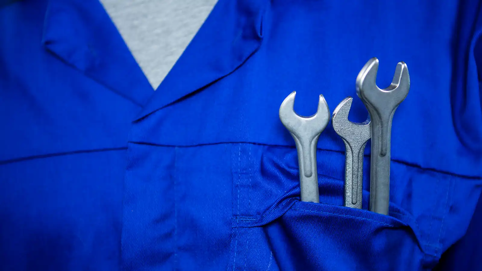 mechanic with wrenches in pocket background