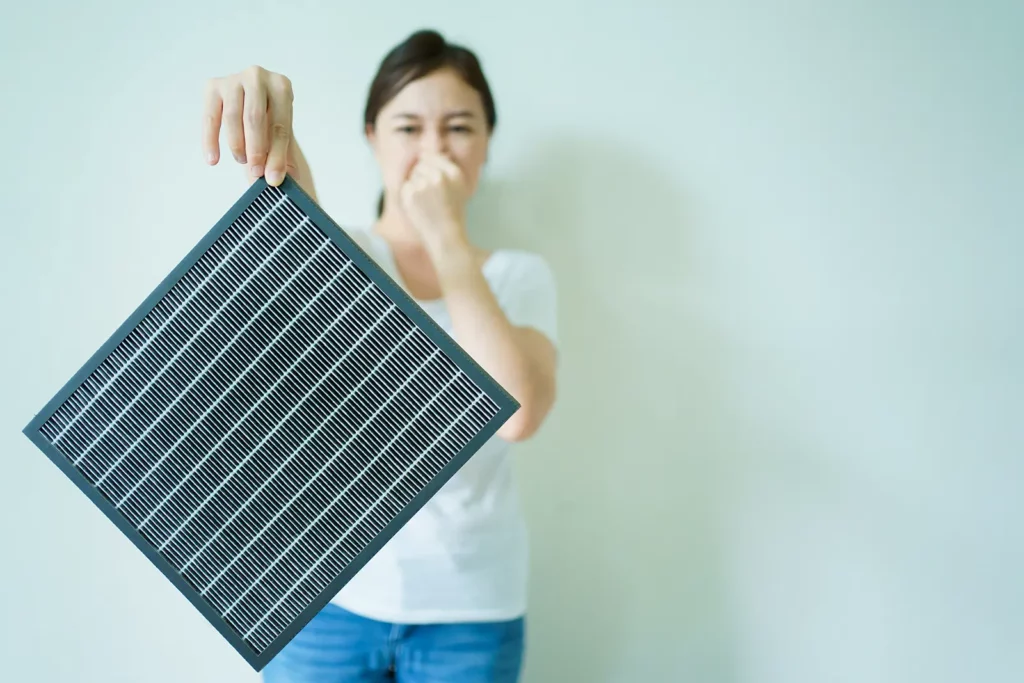 a woman holding her nose and holding a dirty filter